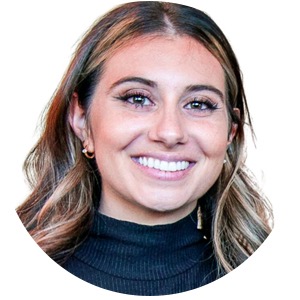 Head shot of a woman who is smiling and is wearing a dark sweater.