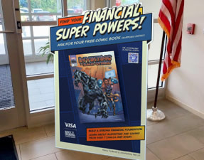 A Visa Marvel in-branch standee sign at the front entrance of a Navy Federal Credit Union